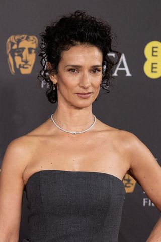 Indira Varma is seen with a curly bun whilst attending the 2024 EE BAFTA Film Awards at The Royal Festival Hall on February 18, 2024 in London, England.