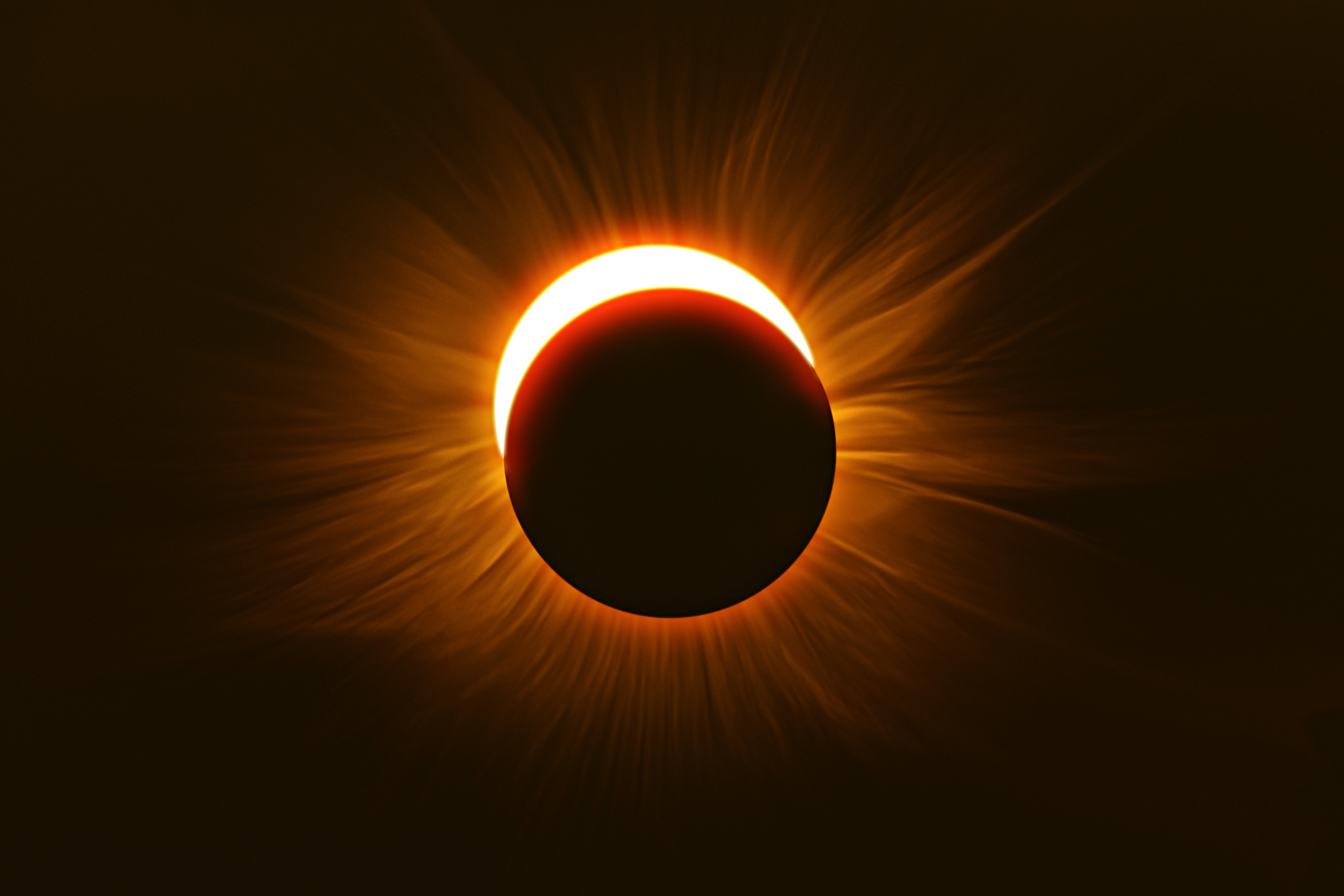 A sliver of sun beaming out from behind the shadow of the moon during a solar eclipse