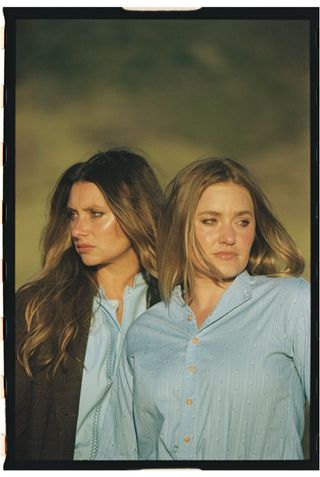 aly and aj wear matching blue shirts posing together outside in a promo shot for their album silver deliverer