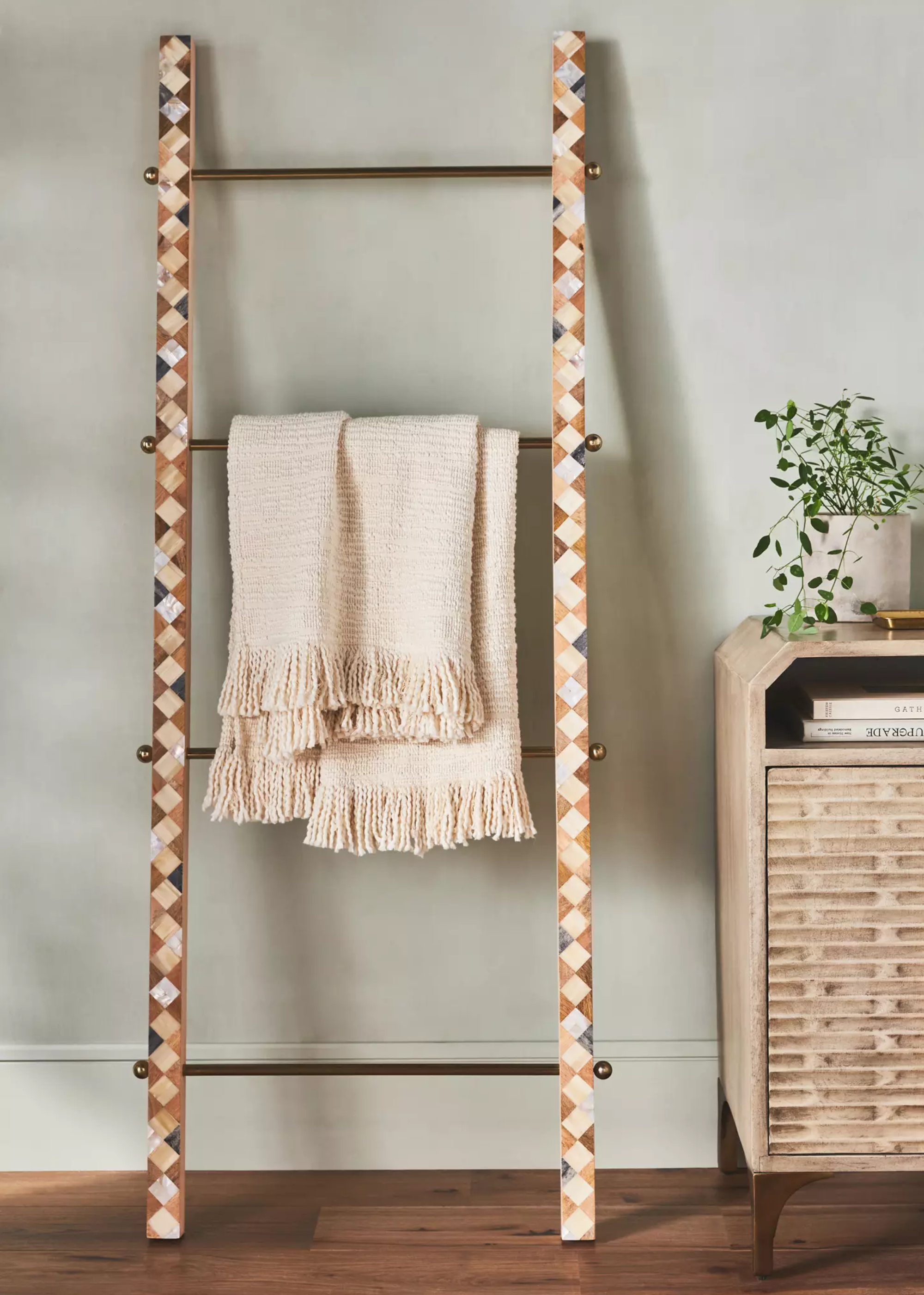 A ladder with a fringed scarf draped on a rung