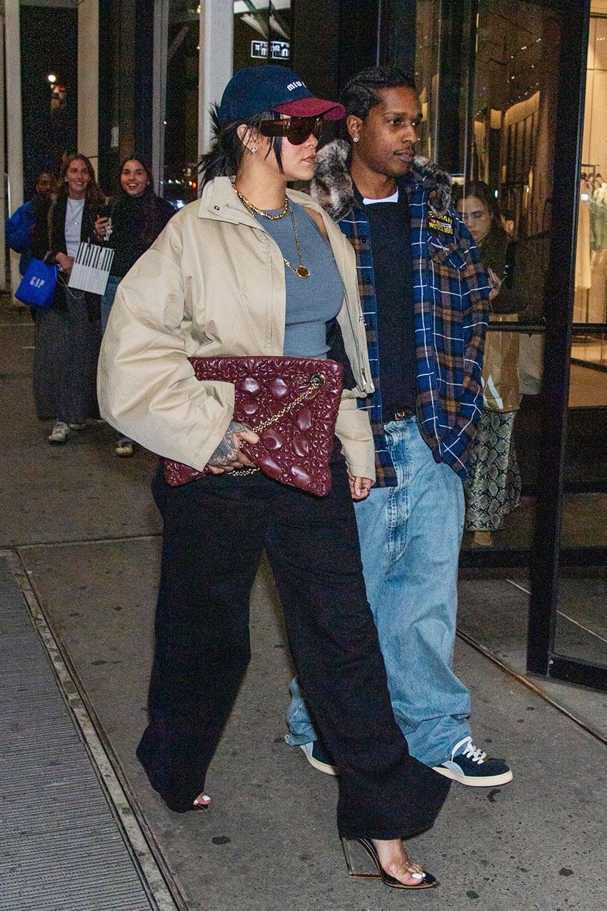 Rihanna wearing a two-toned Miu Miu baseball cap, gray tank top, black belt, black pants, burgundy Dior bag