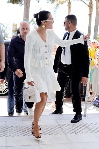 Selena Gomez aparece en Cannes con un atuendo completamente blanco que incluye un bolso blanco y gafas de sol. 