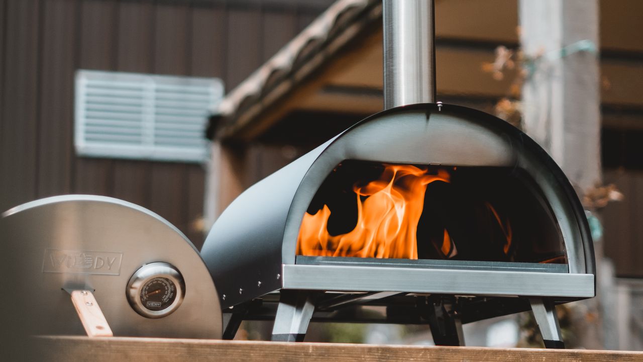 Woody pizza oven with door off showing flame