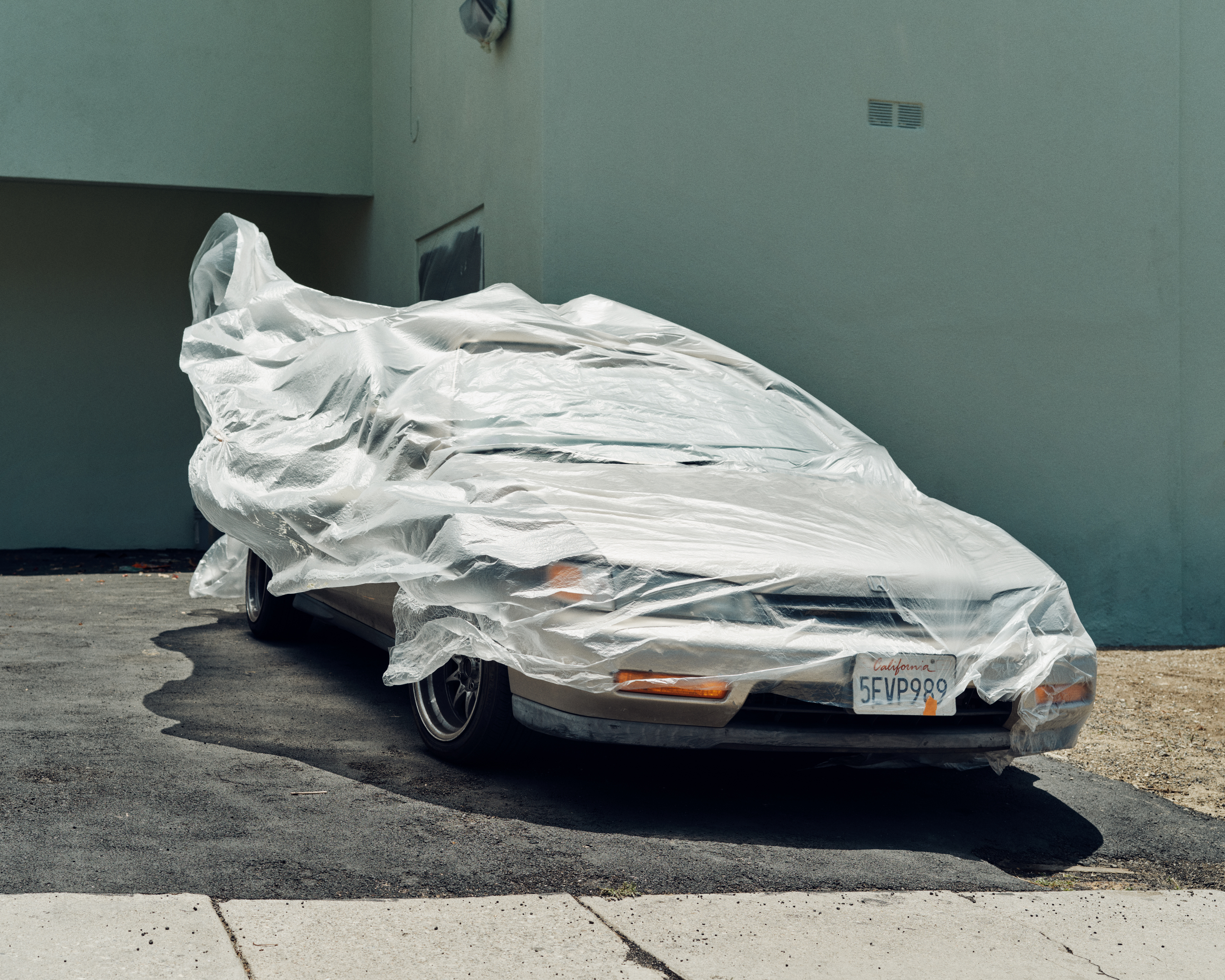 photography of a car on a driveway with a cover on it, blowing in the wind