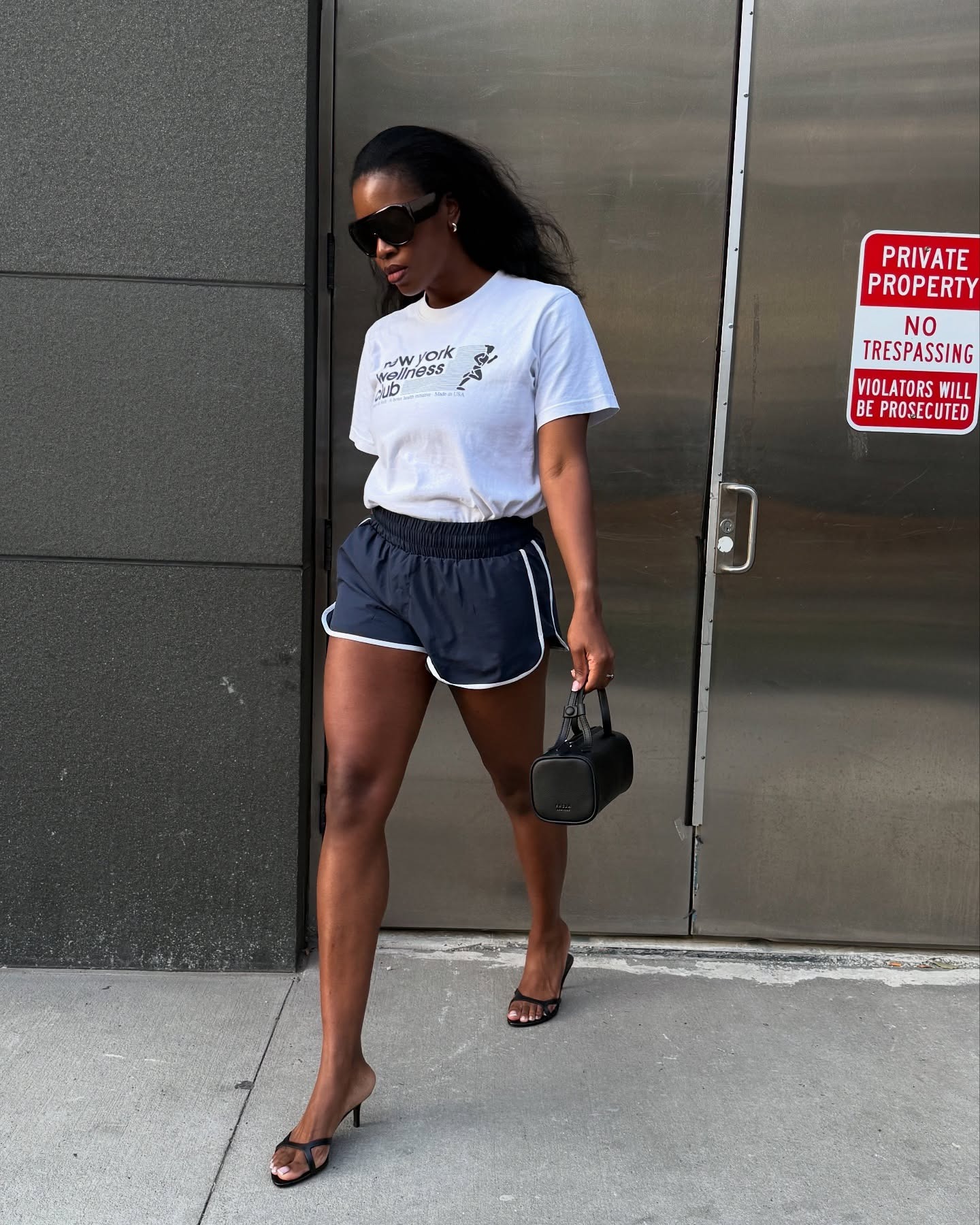 Influencer @nlmarilyn wears a white t-shirt tucked into sports shorts with heeled sandals.