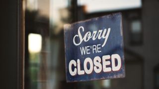Sign in shop window saying 'Sorry, we're closed'