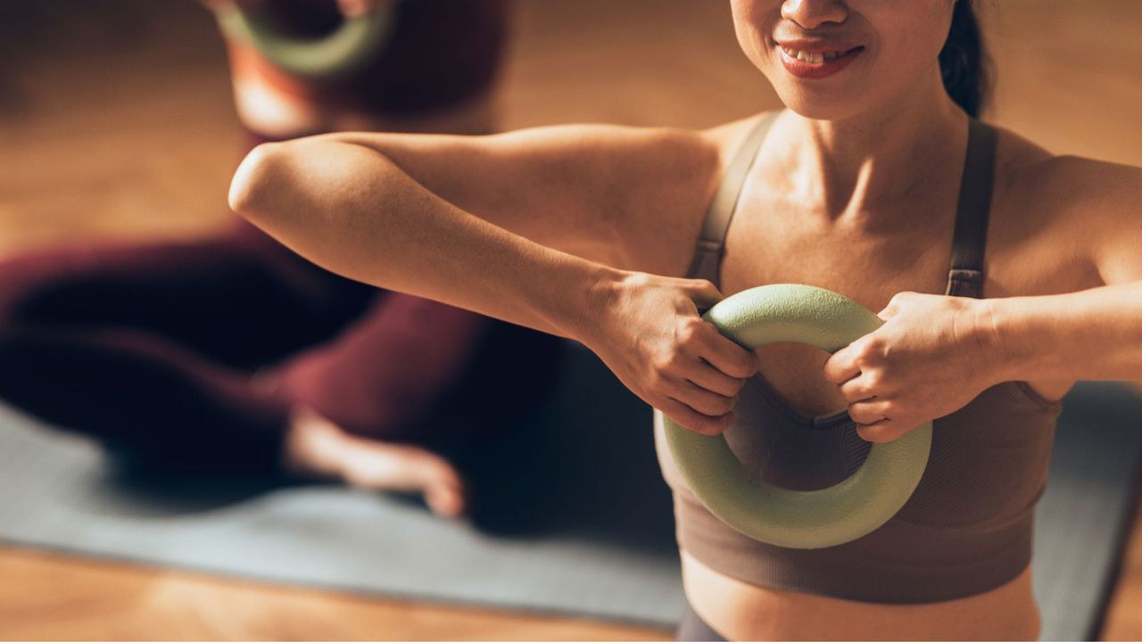 A woman doing some of the most advanced Pilates exercises in a studio holding a Pilates ring