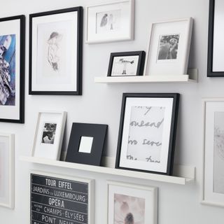 a gallery wall using picture rails comprised of various images, set against a white wall