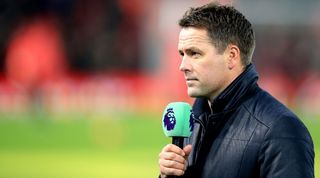 Michael Owen holds a microphone bearing the Premier League logo