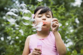 mud kitchen ideas: girl blowing bubbles