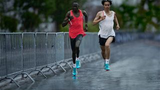 Two athletes running on a street while it's raining