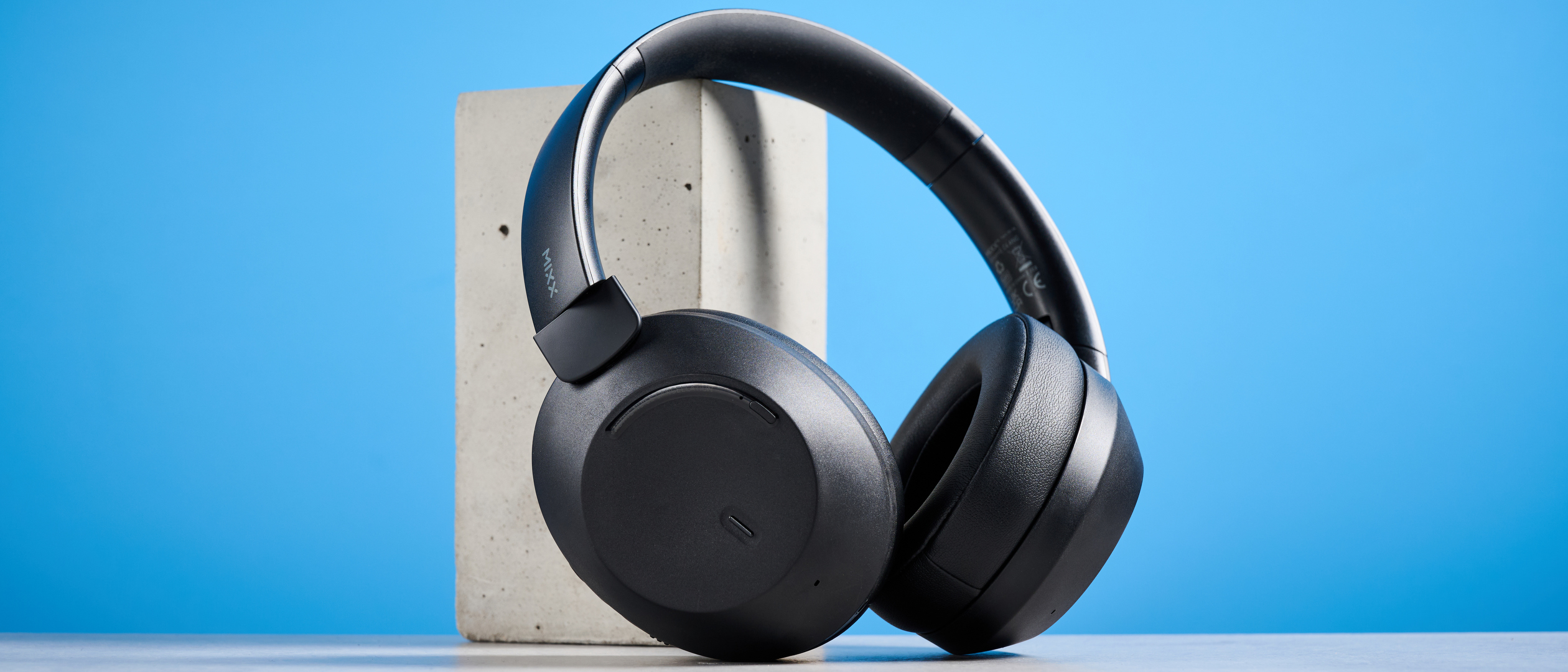 the mixx streamq c4 headphones in black with a blue background showing the soft cups and buttons controls