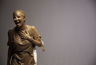 a photo of Joanne Salley covered in mud laughing with a grey background