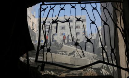 Palestinians look through destroyed home