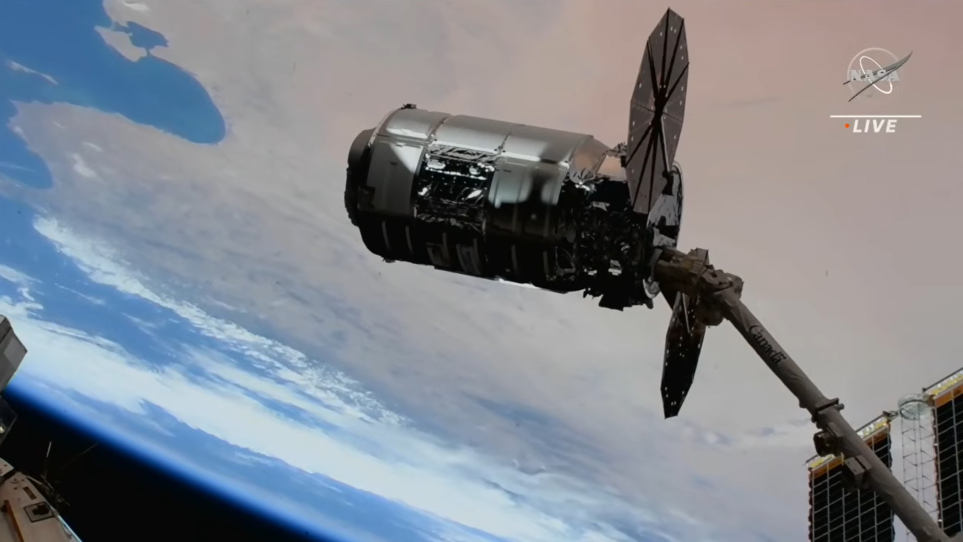 cygnus spacecraft with solar wings visible against the earth. the nasa logo is in the corner