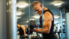 A muscular man performing bicep curls at the gym