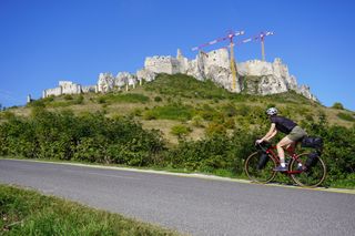Image shows Anna cycling towards Spiš Castle in Slovakia