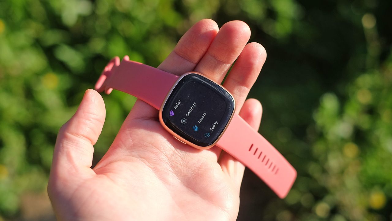 Fitbit Versa 4 being held in a hand outside