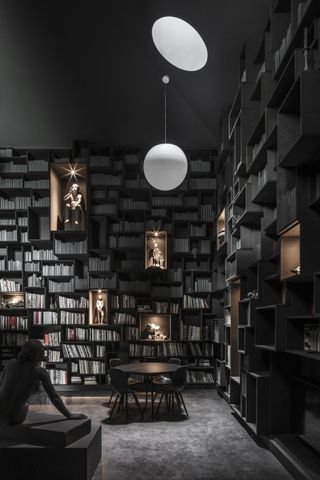 Interior with library book shelves and spotlit sculptures