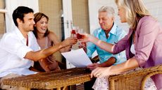 Wealthy family on porch with paperwork raising wine glasses in celebration