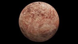 A reddish brownish planet sits in the darkness of space