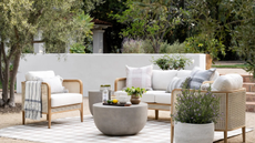 outdoor sitting area with a sofa, two chairs, a rug, and a small coffee table