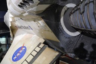 Space shuttle Atlantis' main engines and left wing are revealed after their shrink wrap covering is removed in preparation for the orbiter's display at the Kennedy Space Center Visitor Complex in Florida, April 25, 2013.