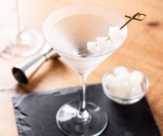 A martini glass with a slate and jigger in the background
