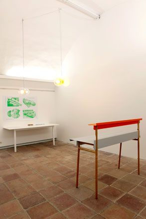 Room featuring white walls and brown tiled concrete flooring with a high bench and a white table against the wall