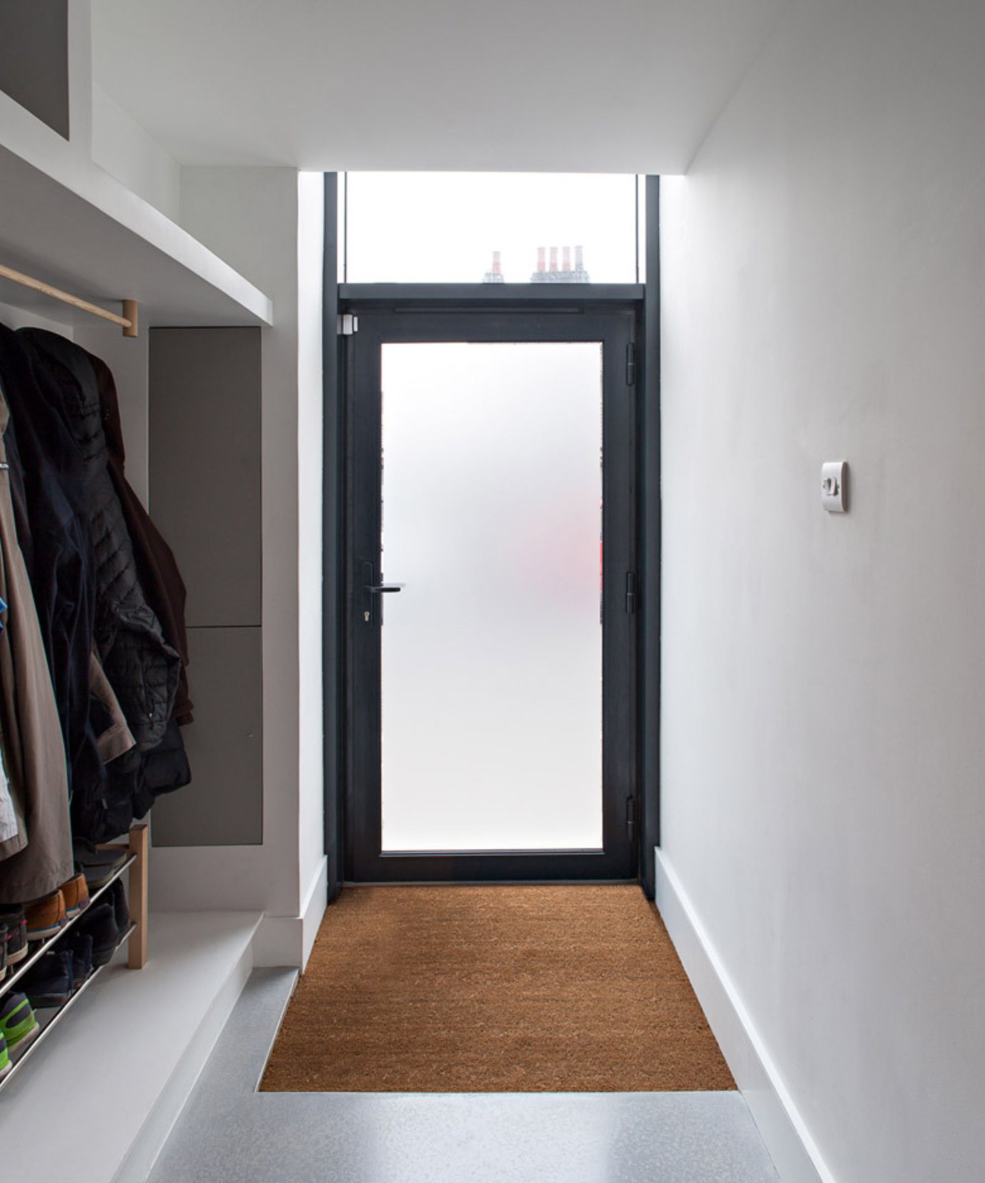 A hallway with a glass front door and built in storage