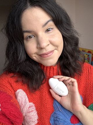 Mica Ricketts holding bottle of Lisa Eldridge Seamless Skin Enhancing Tint to show on skin