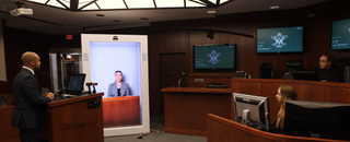 A hologram of a witness sits in court. 