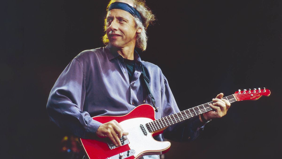 Mark Knopfler wears a headband and plays a red Telecaster