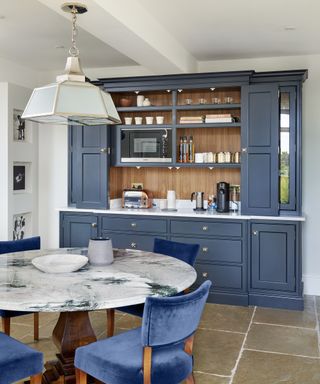 An example of kitchen cabinet ideas showing a blue and white marble table with blue upholstered chairs