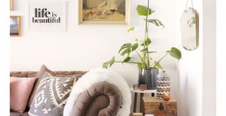 white living room with brown leather sofa and gallery wall wih artwork that reads Life is beautiful to show how to rning positive energy into your home