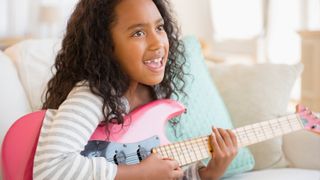 Young girl holds a pink electric guitar