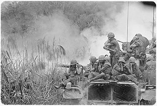 Vietnam....Marines riding atop an M-48 tank cover their ears as te 90mm gun fires during a road sweep southwest of Phu Bai.