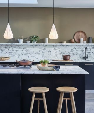two pendant lights with white fluted style teardrop shaped shades hanging over marble topped kitchen island
