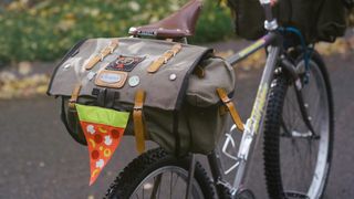 A large canvas saddlebag with a reflective pizza attached to it