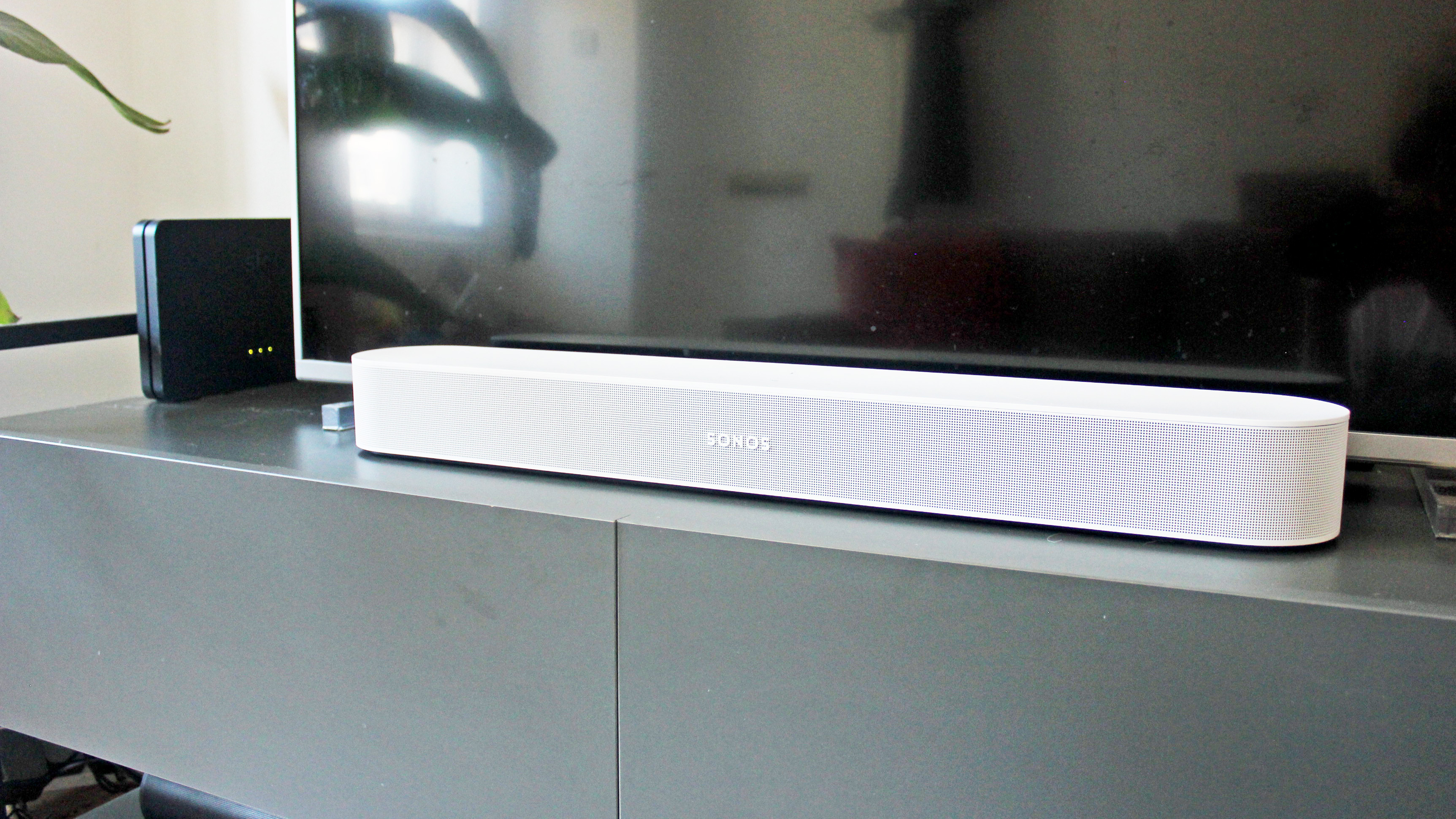 the sonos beam gen 2 soundbar in white on a tv cabinet under a TV display