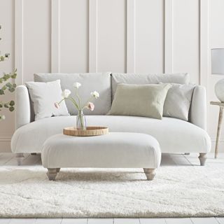 light grey sofa and matching pouffe on legs in neutral living room