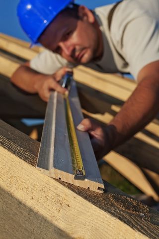 Construction worker measuring wood.