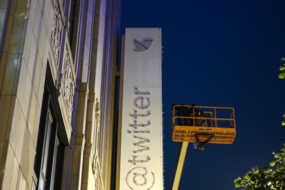 Workers take blue bird and the letters off from Twitter sign on headquarters