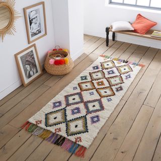 This white rug with colorful diamond shapes is finished off with multi-colored tassles 