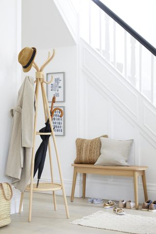 white hallway with pale wood coat rack and bench