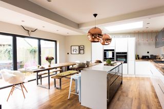 A garage converted into a modern open plan kitchen diner with wooden floors, a dining table and a white island