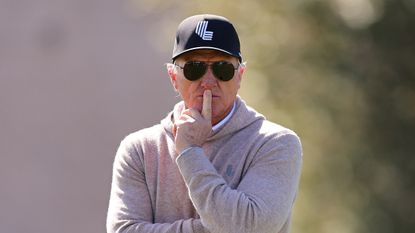 LIV Golf CEO Greg Norman stands with his finger on his mouth and a black LIV Cap on at LIV Golf Jeddah