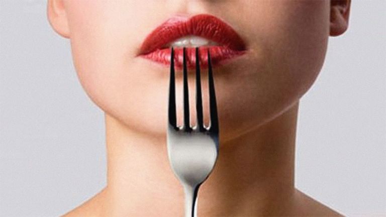 woman with red lipstick pressing a fork to her lips