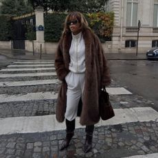 Ellie Delphine wears track pants with a faux fur coat.