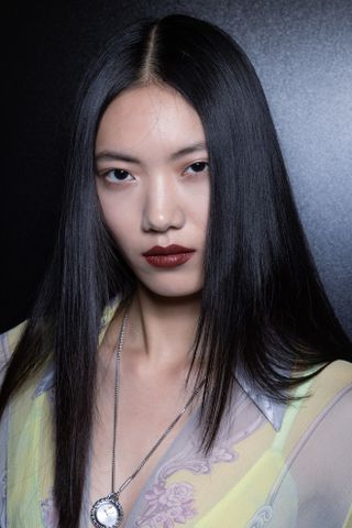 Model at versace backstage spring 2025 show wearing dark red lipstick